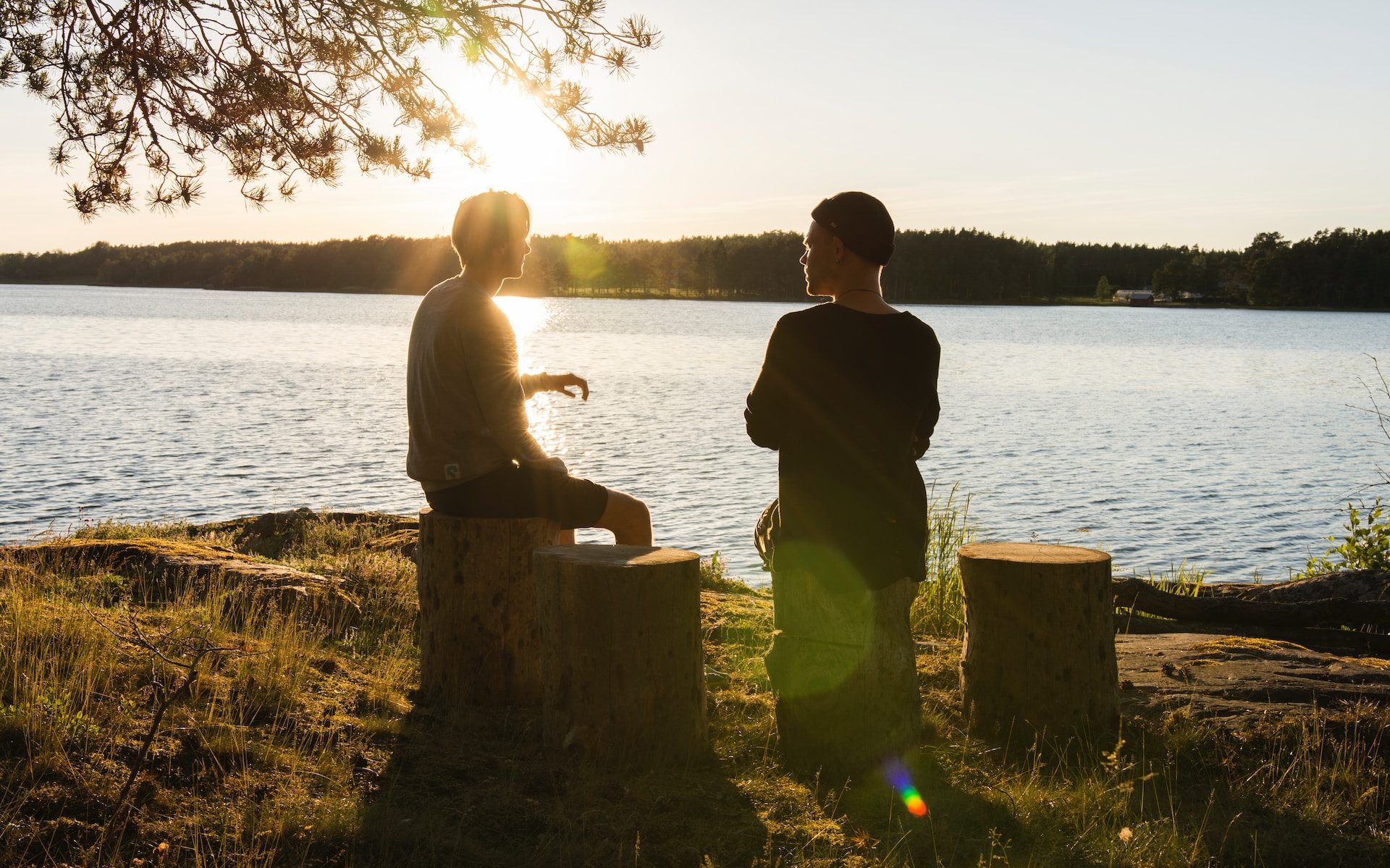 man in black jacket standing beside body of water during sunset